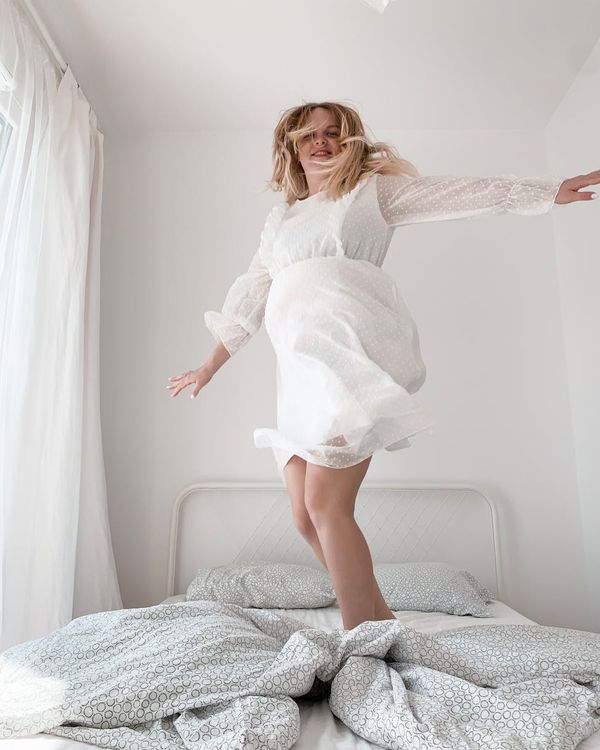 Smiling woman stretching joyfully, radiating positive energy in a sunlit room.