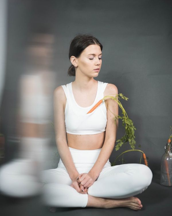 Woman in a calm yoga pose, embodying harmony and balance in a minimalist white studio.